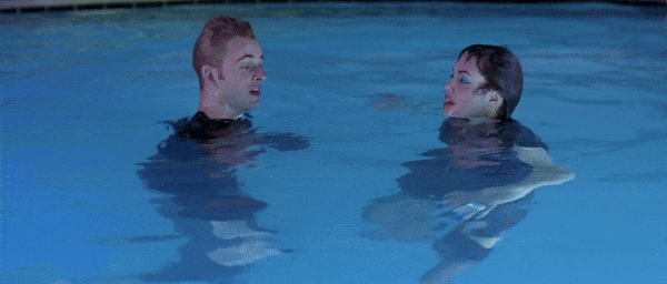 GIF of scene from Hackers (1995) film. Dade Murphy and Kate Libby, fully clothed, tread water in a swimming pool. Dade looks off into distance then back at Kate, who looks up to realize something and starts laughing and smiling. Dade smiles in satisfaction.