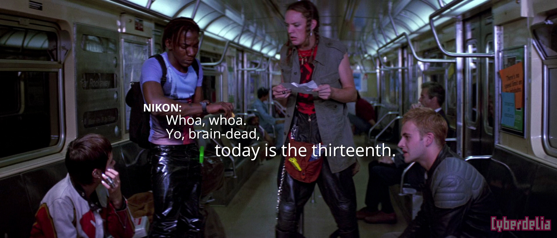 Scene from Hackers (1995) movie: character Kate/Acid Burn, Lord Nikon, Cereal Killer and Dade Murphy gathered in a subway car, holding computer paper printouts and talking. Lord Nikon and Cereal standing at center with puzzled looks, Nikon looking at his watch. Kate and Dade seated on opposite sides looking up at them. Large white text overlaid: NIKON: 'Whoa, whoa. Yo, brain-dead, today is the thirteenth.'